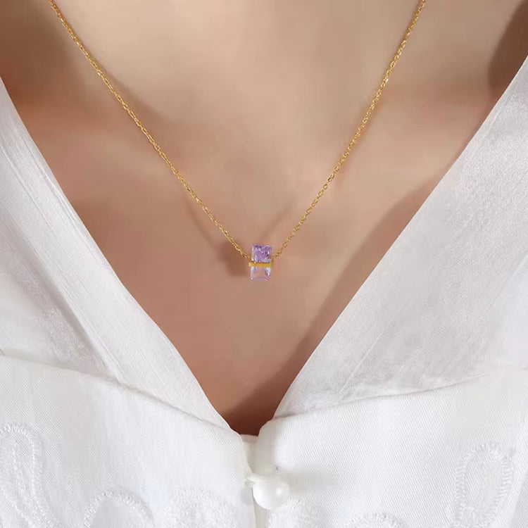 Gold necklace with a purple gemstone pendant on a mannequin wearing a white blouse.