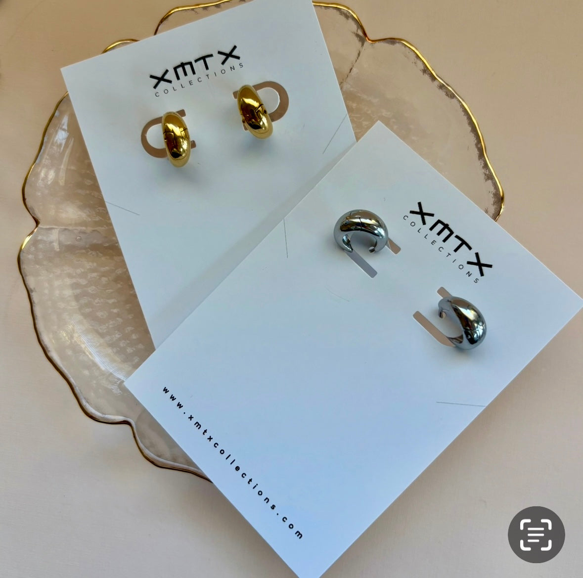 Gold and silver earrings on ELSSIZ Collection cards with a beige background