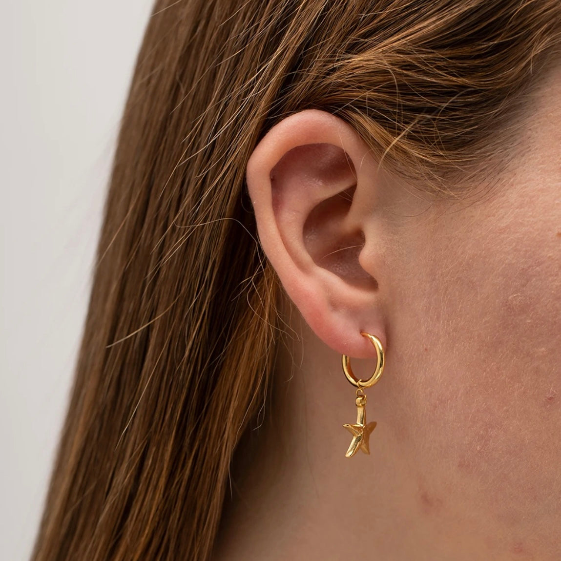 Starfish Huggies Earrings ELSSIZ shown on an ear