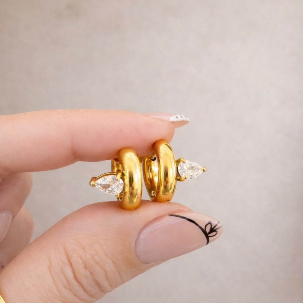 Elle Huggies gold teardrop stone huggie earrings close-up in hand