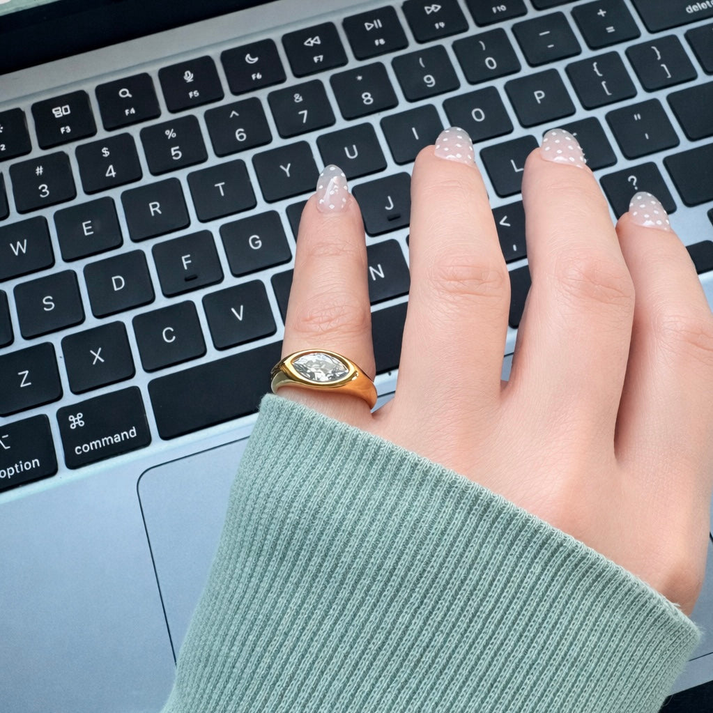 Gold marquise clear stone ring worn on hand typing on laptop, everyday waterproof gold jewelry