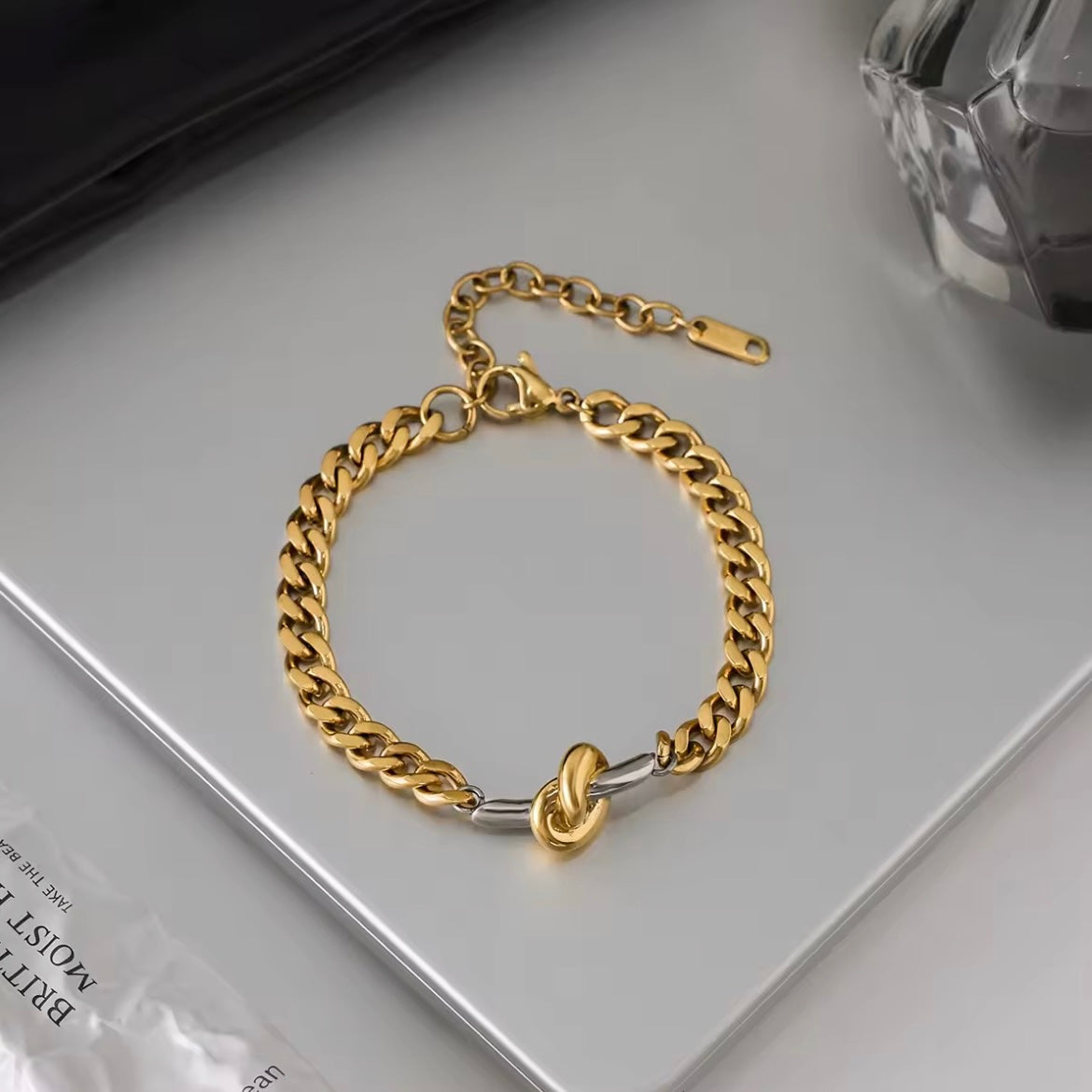 Gold and silver two tone curb chain bracelet on neutral surface modern waterproof jewelry