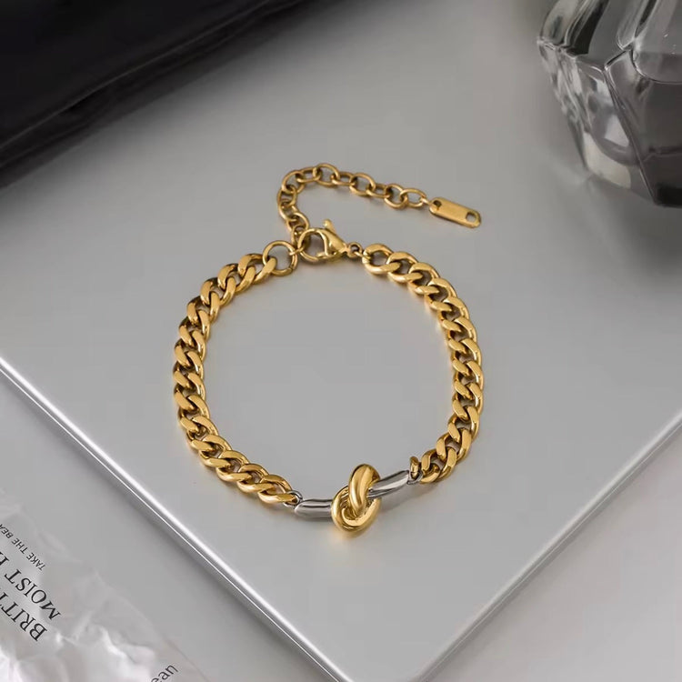 Gold and silver two tone curb chain bracelet on neutral surface modern waterproof jewelry