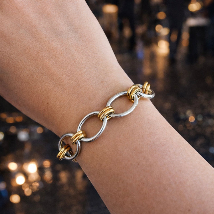 Woman wearing Tessa two tone stainless steel bracelet with gold and silver links styled for a night out.