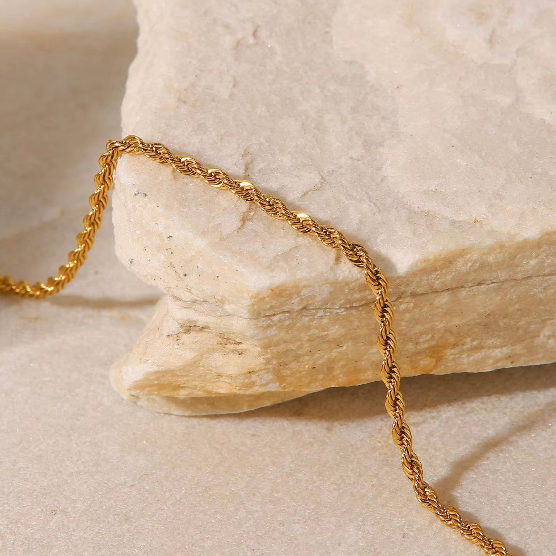 Close-up of silver twisted rope anklet bracelet on a stone