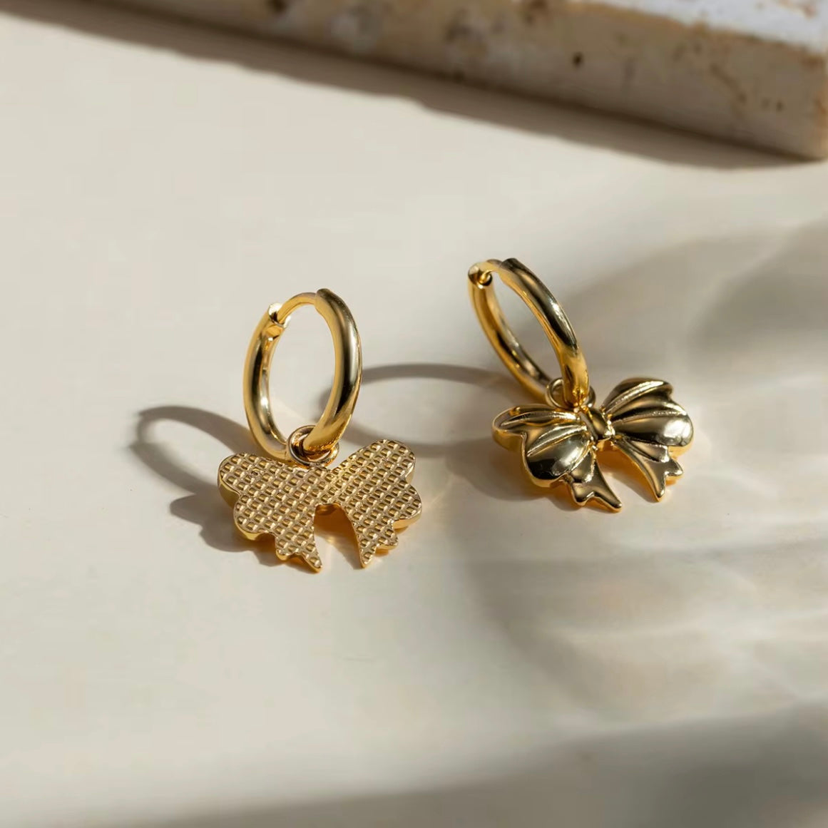 Embrace the latest trend with our must-have Bow Huggies Earrings. These cute accessories add a touch of charm to any outfit. Expertly crafted and designed to hug the ear, they are the perfect addition to your jewelry collection.

Made to last!&nbsp;Tarnish and Water Resistant, Beach &amp; Shower friendly, Hypoallergenic

.82" total length from the hoop the the tip of the bow

18K Gold Plated over 316L Stainless Steel base